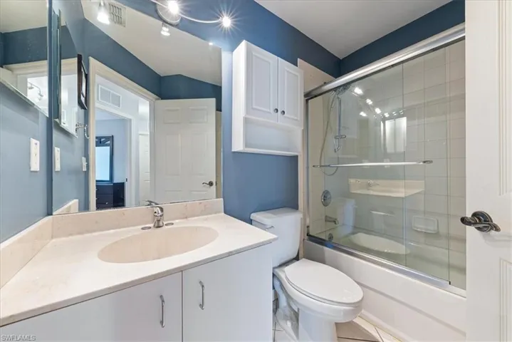 Bathroom with toilet, combined bath / shower with glass door, vanity, and visible vents