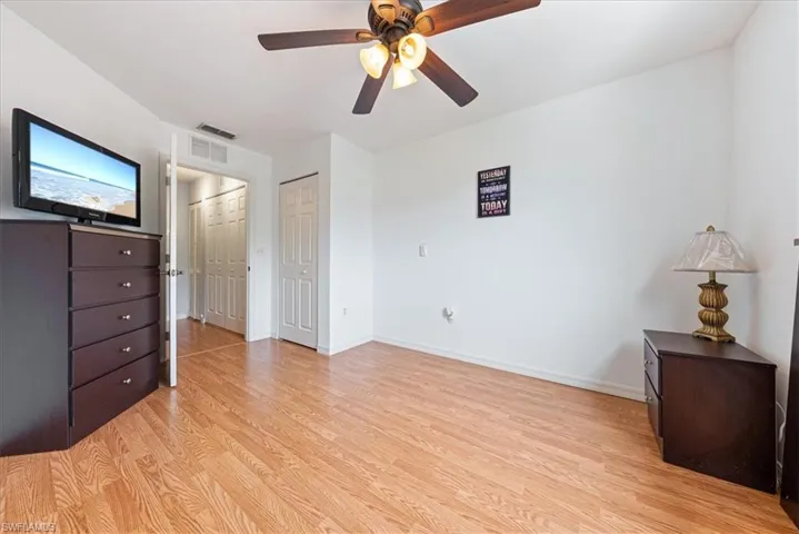 Unfurnished bedroom featuring light wood-type flooring, visible vents, two closets, a ceiling fan, and baseboards