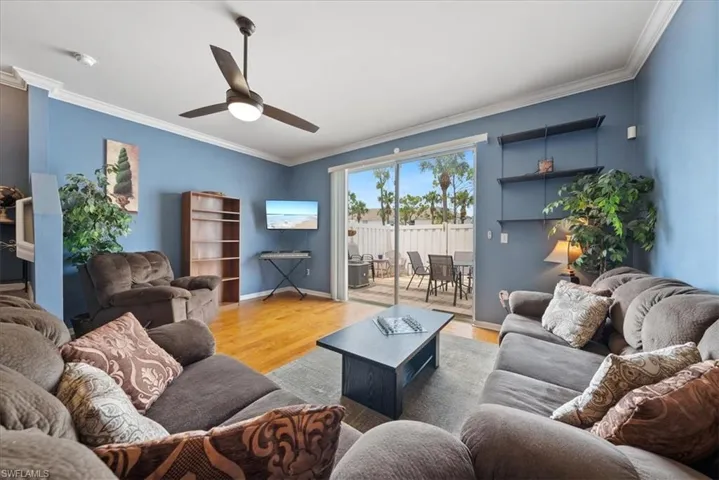 Living area with baseboards, ornamental molding, ceiling fan, and wood finished floors