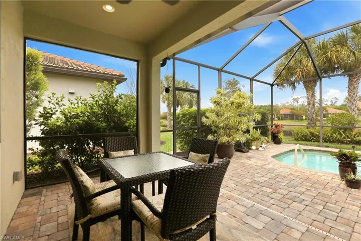 View of patio featuring an outdoor pool, a screened in lanai, and outdoor dining space - All while enjoying your Palm Trees and Lake Views.