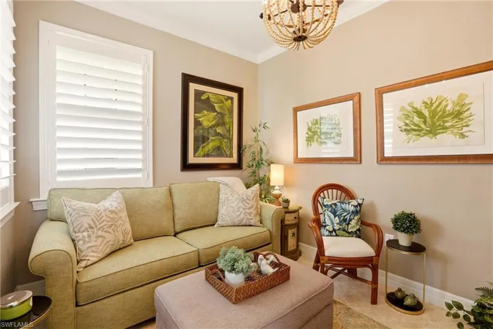 Den with hanging lights, ornamental molding, and tile patterned floors