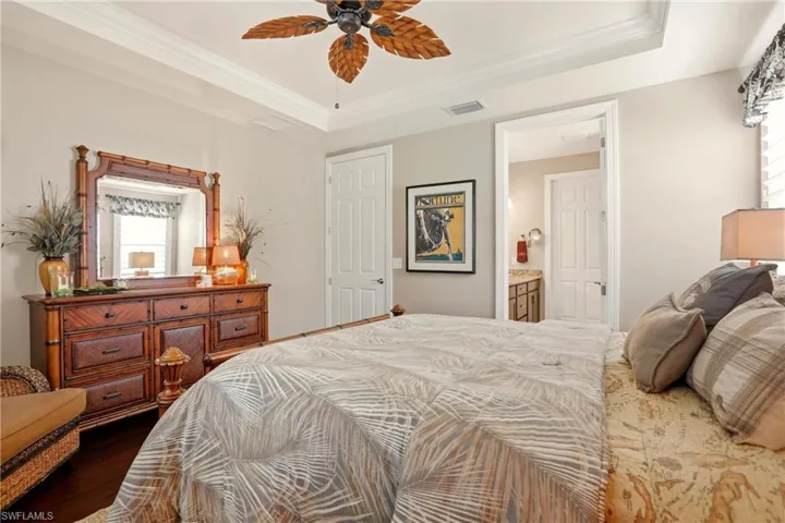 Primary Bedroom with wood finished laminate floors, ornamental molding, ceiling fan, and ensuite bath