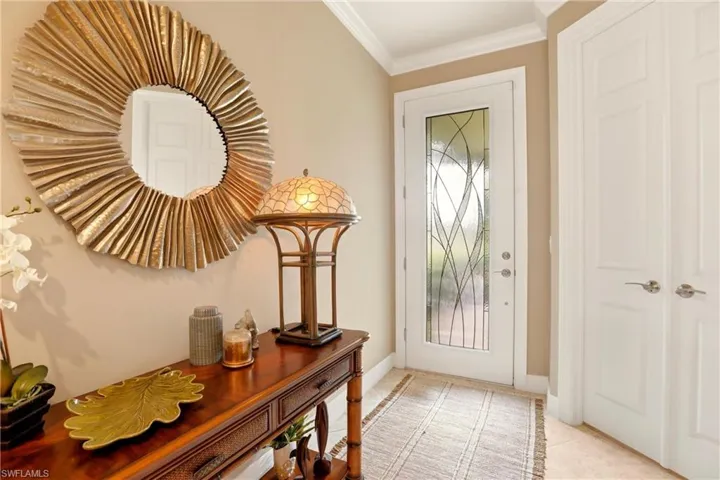 Entrance foyer with Crown molding and light tile patterned floors and lead glass front door.