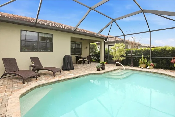 Swimming pool featuring glass enclosure, outdoor dining space, and a patio
