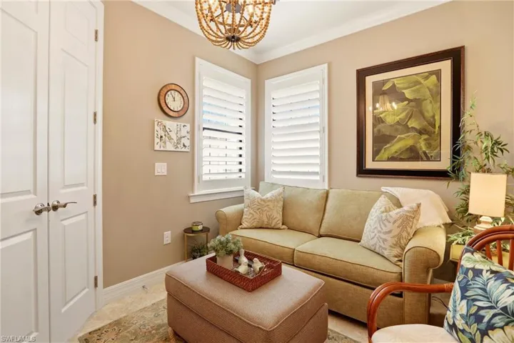 Den with hanging lights, crown molding, and tile patterned floors