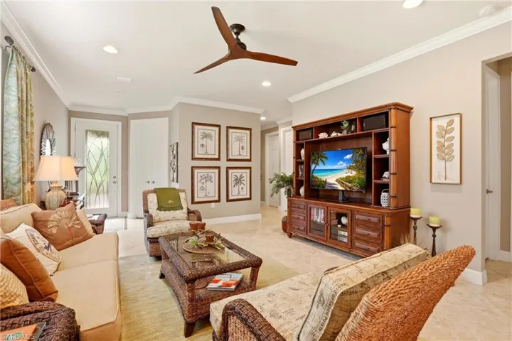 Crown molding, a ceiling fan, recessed lighting, and light tile flooring on the diagonal.