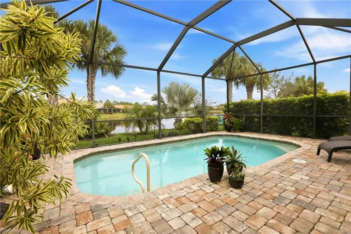 Swimming pool featuring a water view, glass enclosure, and a sunroom