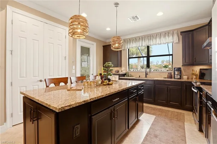 Kitchen with dark wood finish cabinets, light granite counters, decorative backsplash, and crown molding