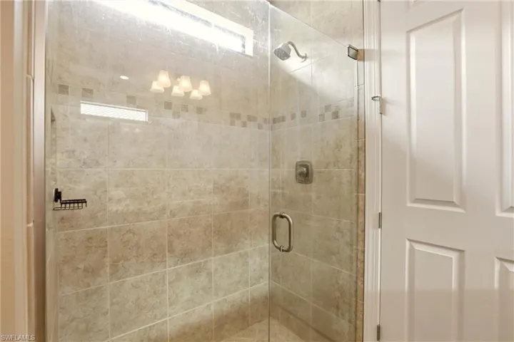 Primary Bathroom featuring a frameless glass shower and tile all the way to the ceiling.
