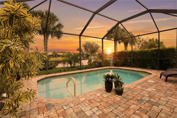 Pool at dusk with an outdoor pool, a sunroom, and screened enclosure