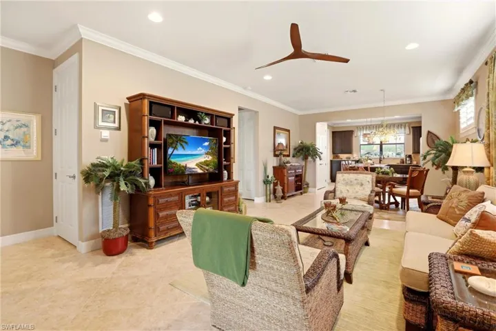 Living room with a ceiling fan, crown molding, and suspended lighting