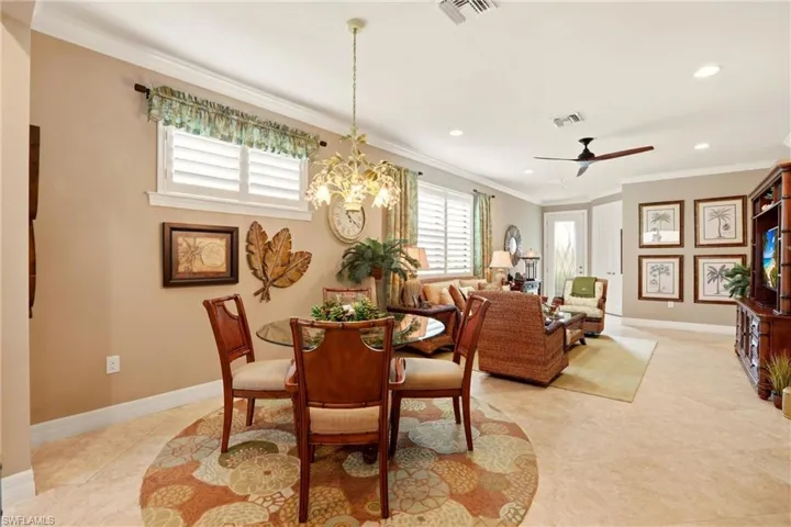 Dining area with crown molding, a chandelier, ceiling fan, and light tile floors