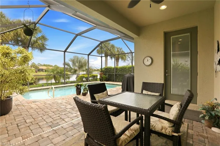 View of patio with an outdoor pool, screened enclosure, a ceiling fan, and a water view to invite complete relaxation.