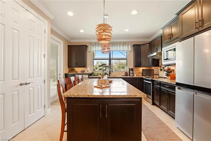 Kitchen featuring a breakfast bar, stainless steel appliances, a kitchen island, dark wood finish cabinetry, and crown molding