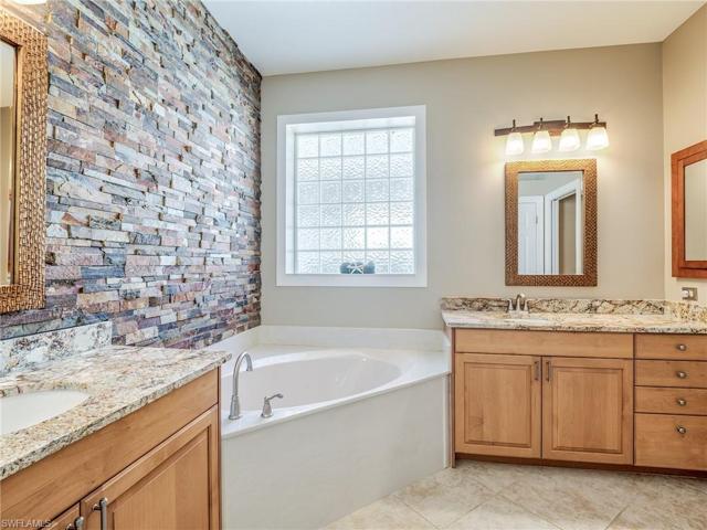 Primary Suite Bath offers Separate Cabinet Sinks, Granite Countertops, Stone Accent Wall, Soaking Tub