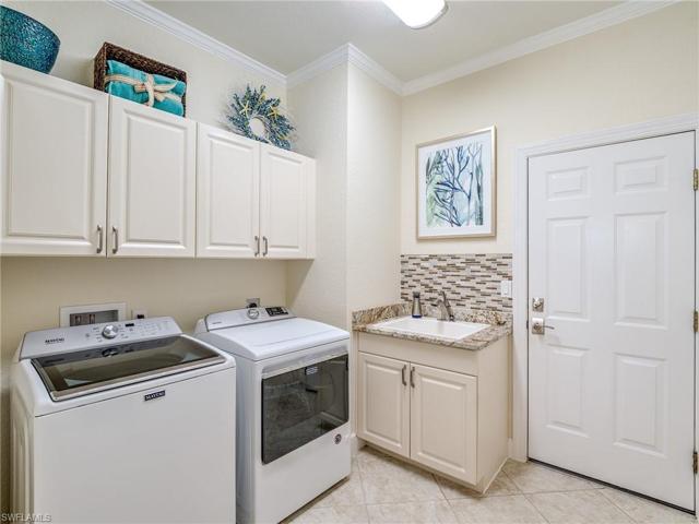 This spacious laundry offers washer, natural gas dryer, utility sink with tile backsplash and a large storage area.