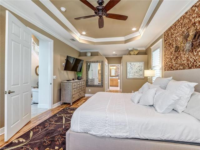 This FIRST FLOOR PRIMARY SUITE offers hardwood floors, Tray Ceiling, Crown Molding, Plantation Shutters, Sliding Doors to Lanai, Walk-in Closets with Frosted Glass doors and Organizers, a beautiful retreat!