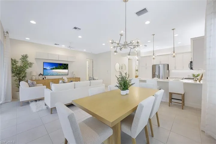 Dining space featuring ceiling fan with notable chandelier and light tile flooring