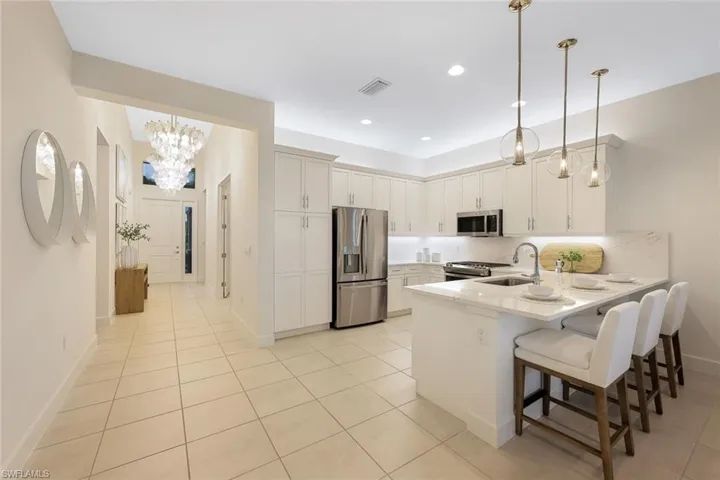 Kitchen with a kitchen breakfast bar, kitchen peninsula, pendant lighting, backsplash, and appliances with stainless steel finishes