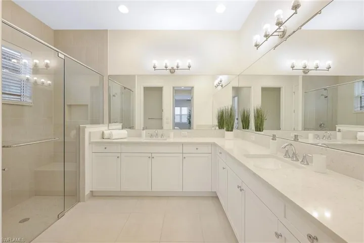 Bathroom featuring dual bowl vanity, walk in shower, and tile floors