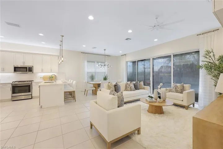 Living room featuring sink, light tile flooring, and ceiling fan with notable chandelier