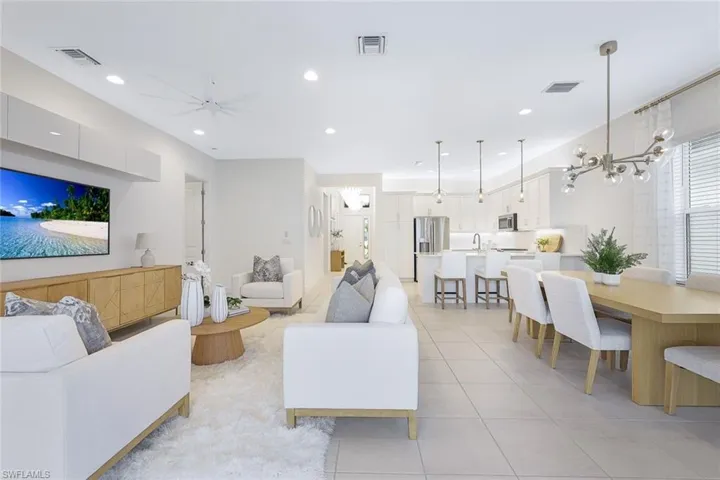 Tiled living room with sink and ceiling fan with notable chandelier