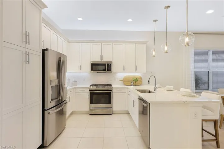Kitchen featuring a kitchen breakfast bar, appliances with stainless steel finishes, kitchen peninsula, backsplash, and sink