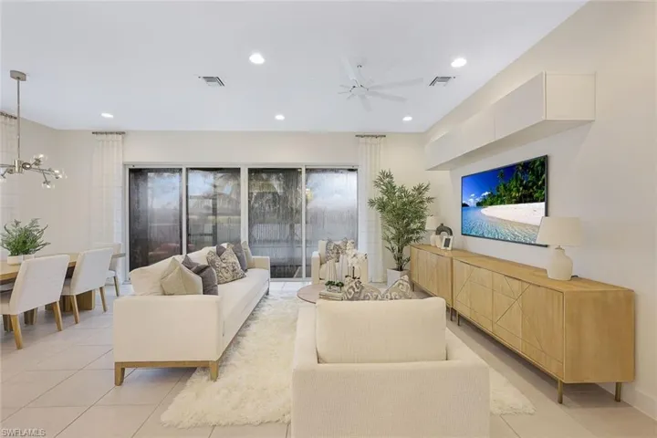 Living room with ceiling fan with notable chandelier and light tile flooring
