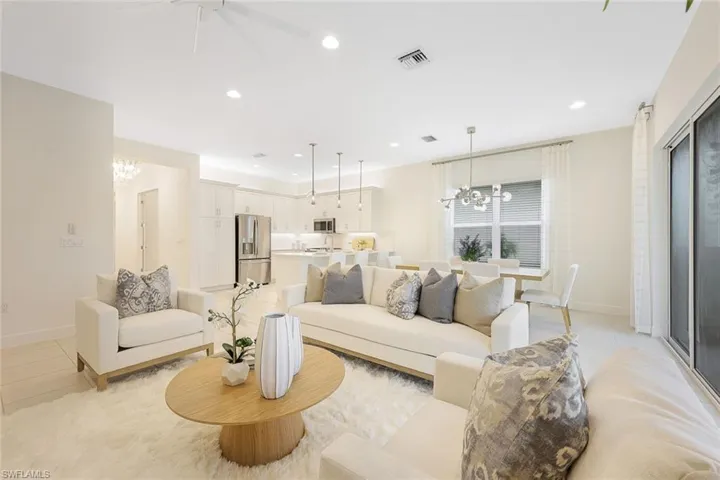 Tiled living room with ceiling fan with notable chandelier