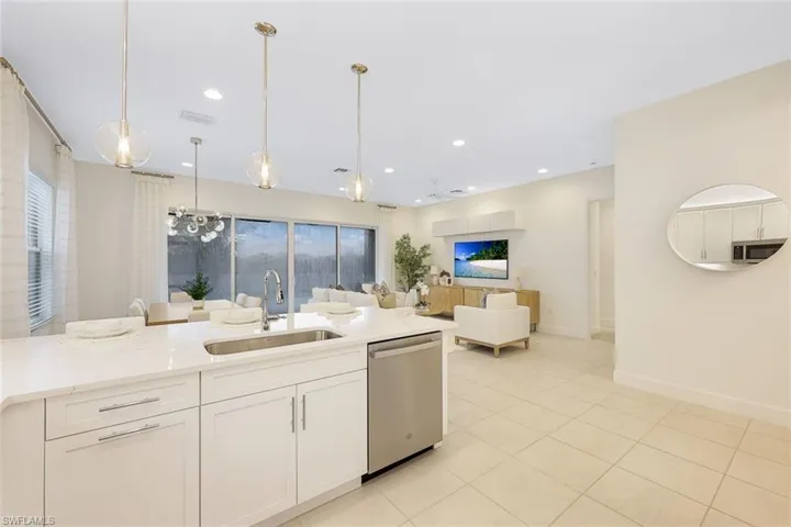 Kitchen featuring light stone countertops, decorative light fixtures, sink, white cabinetry, and appliances with stainless steel finishes