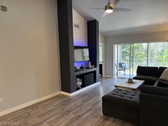 Living room with lofted ceiling, dark wood finished floors, and a ceiling fan