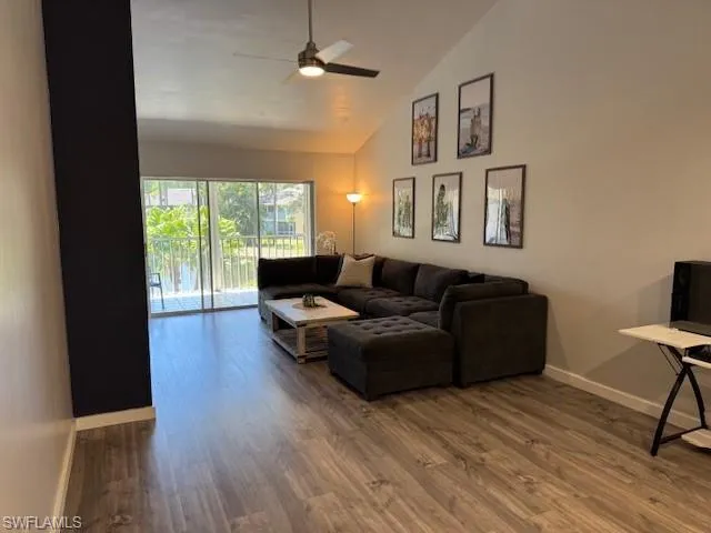 Living room featuring dark wood finished floors, lofted ceiling, and ceiling fan