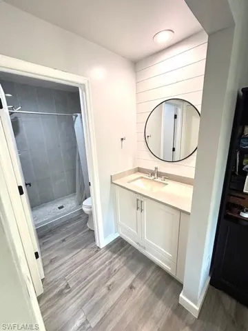 Full bathroom with a shower stall, vanity, and light wood-style flooring