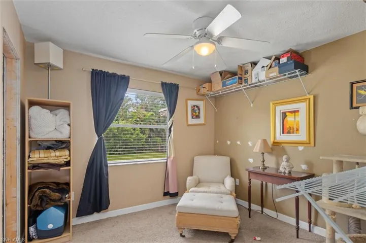 Sitting room featuring a textured ceiling, carpet flooring, and ceiling fan