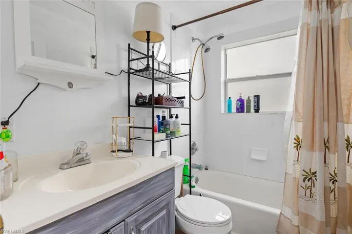 Full bathroom featuring shower / bath combo with shower curtain, toilet, and vanity