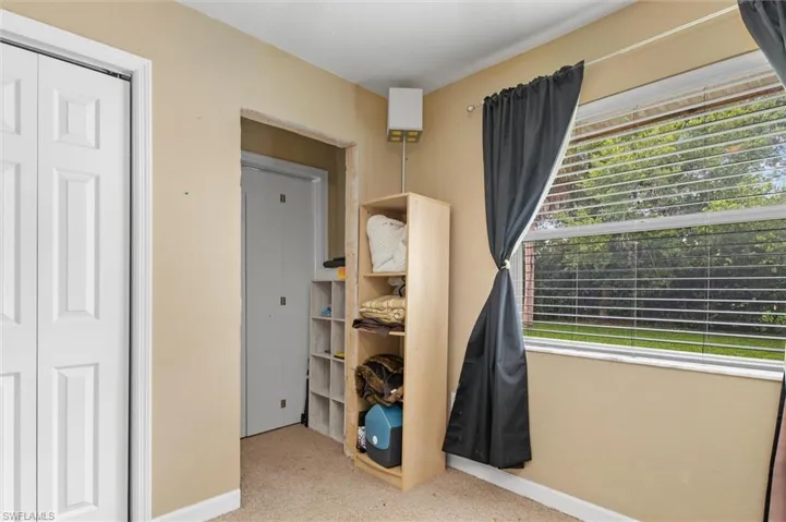 Carpeted bedroom featuring multiple windows and a closet