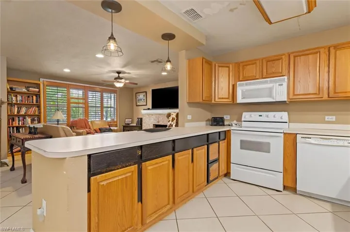 Kitchen featuring decorative light fixtures, white appliances, kitchen peninsula, and ceiling fan