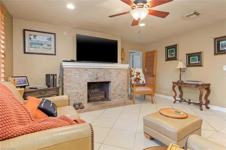 Tiled living room with ceiling fan and a fireplace