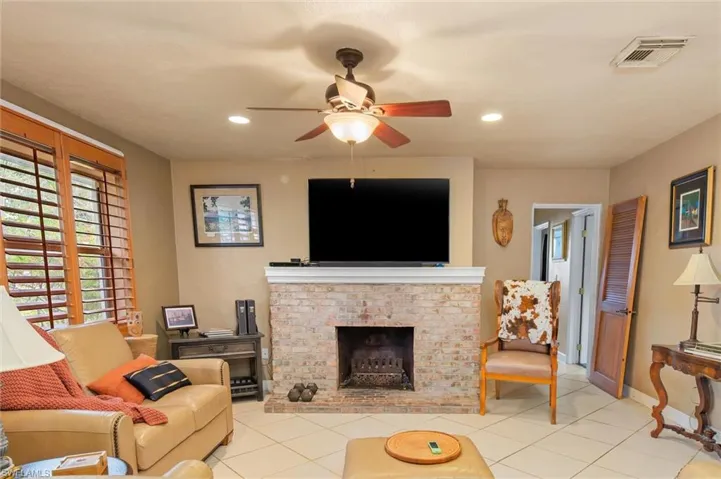 Tiled living room featuring a brick fireplace and ceiling fan