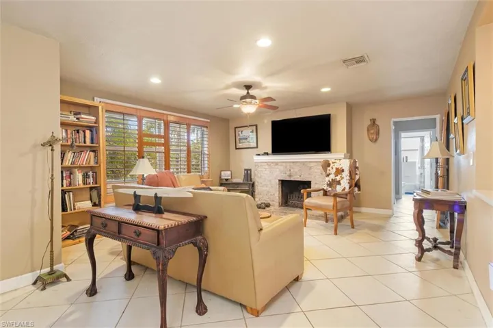 Tiled living room featuring a fireplace and ceiling fan
