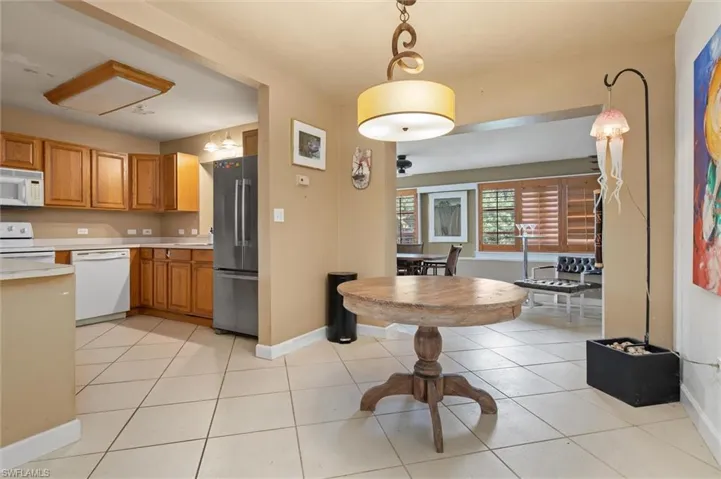 Kitchen with white appliances, light tile flooring, and pendant lighting