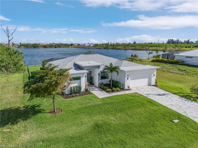 View of front of house with a front yard, a water view, and a garage