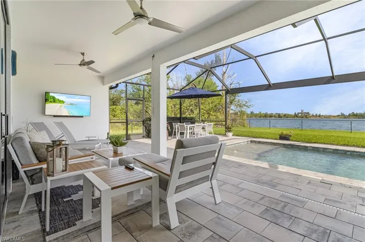 View of patio with a lanai, ceiling fan, and a water view of lake