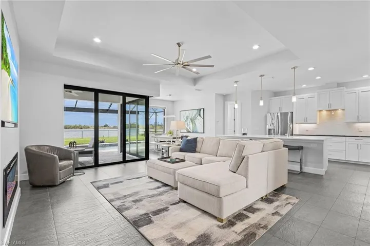 Living room featuring a raised ceiling and ceiling fan