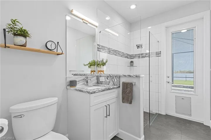 Guest Pool bathroom with tiled shower, vanity, and doggy door