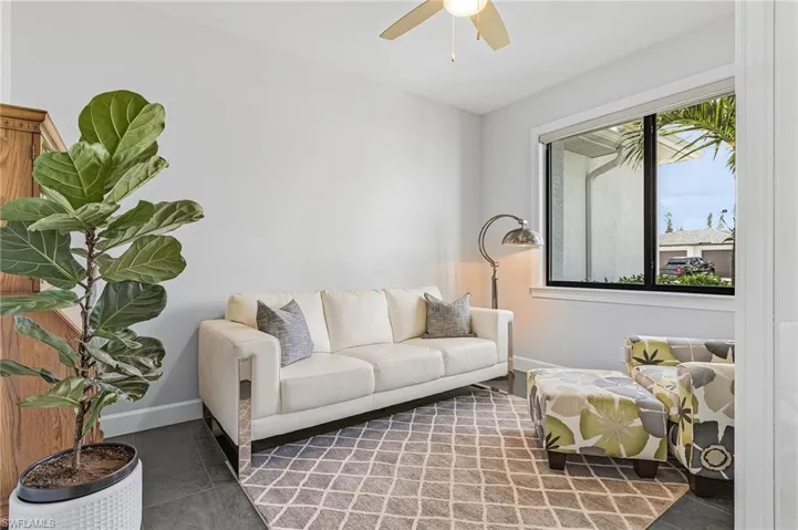 Den with ceiling fan and tile flooring