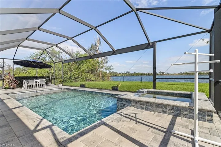 View of swimming pool featuring a lawn, a water view, a lanai, an in ground hot tub, and a patio
