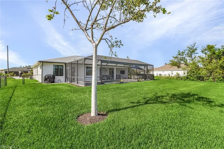 Back of property featuring a lawn, glass enclosure, and a swimming pool
