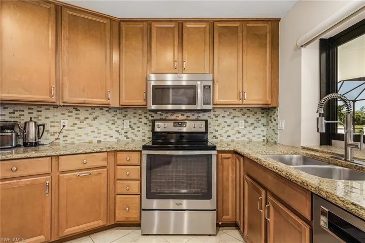 Kitchen with tasteful backsplash, appliances with stainless steel finishes, sink, and light tile patterned floors