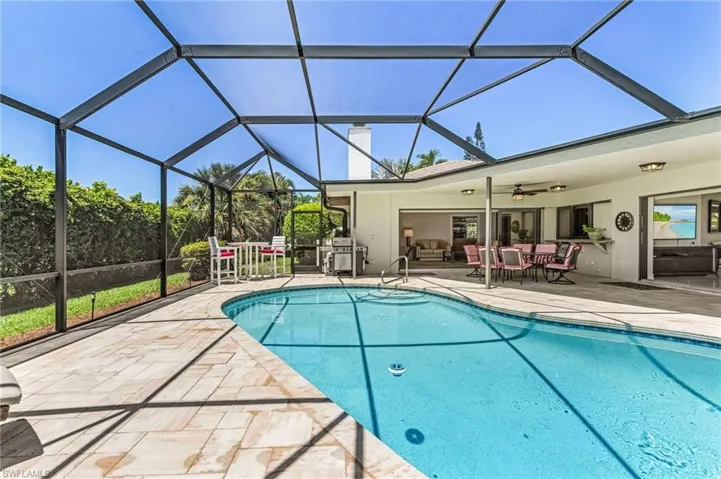 View of swimming pool featuring a patio, glass enclosure, and ceiling fan